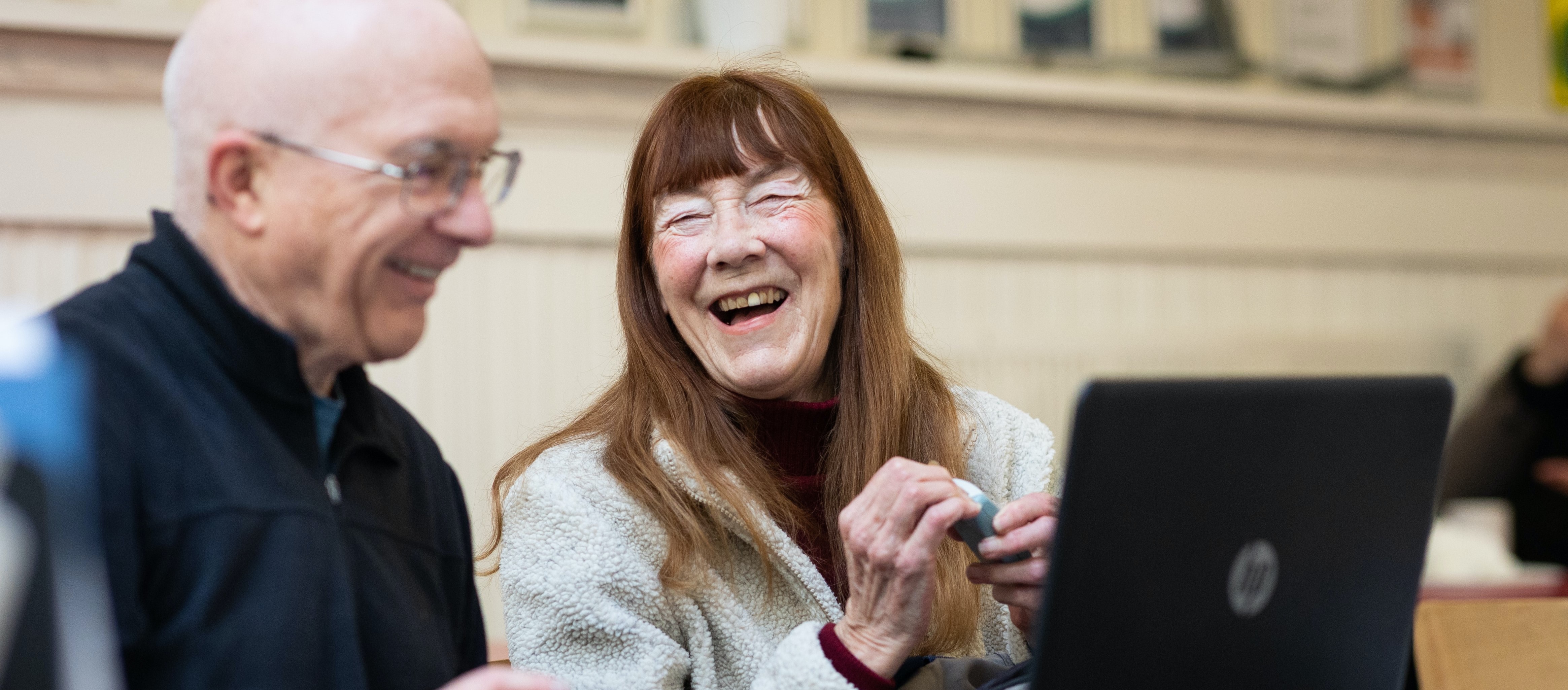 Two older adults laugh with each other. 