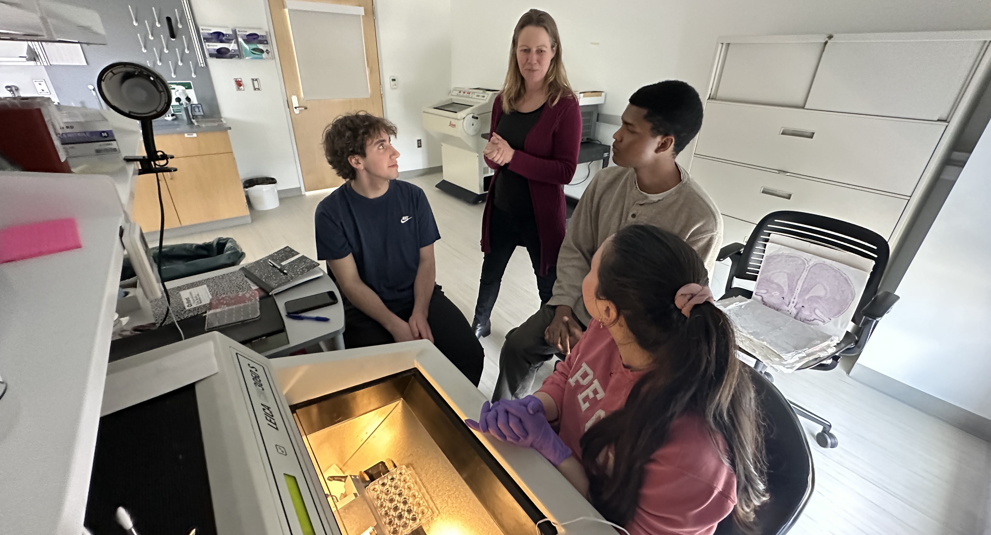 Dr. Veenam and three students talk in their lab.