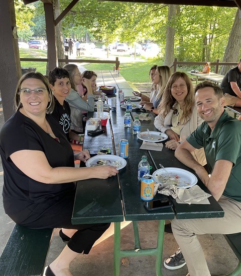 Clinical Science faculty and students sit at a picnic table and look at the camera.