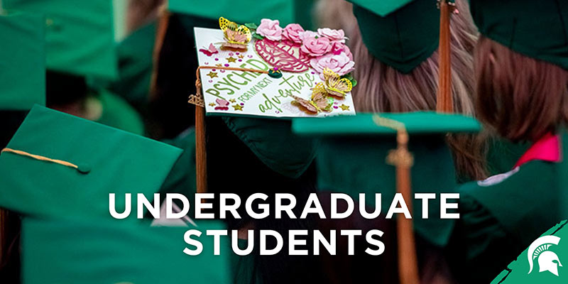 Large text reads Undergraduate Students with the MSU Spartan logo in the corner. The image is of a sea of green graduation hats with one saying "psyched for my next adventure."