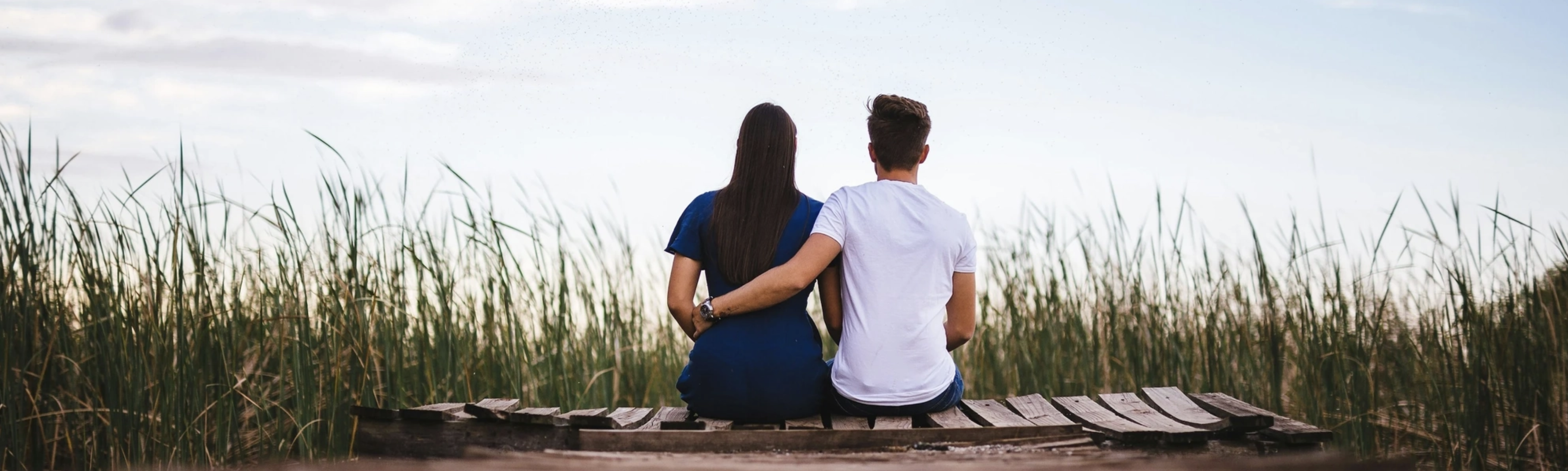 Two adult sit together with their backs facing.