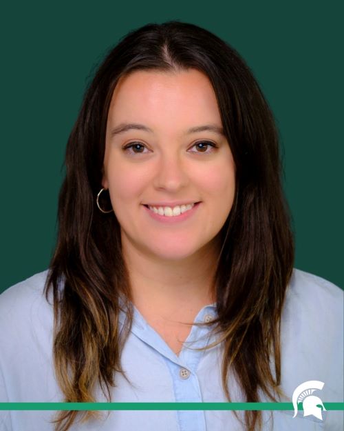 A studio portrait of Abby Cassario with a green background and a Spartan logo at the bottom.