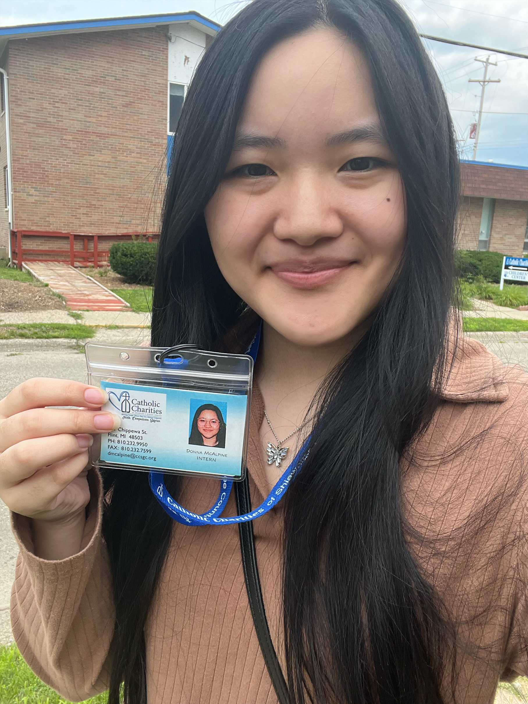 Donna holds her id badge up outside of the Catholic Charities building