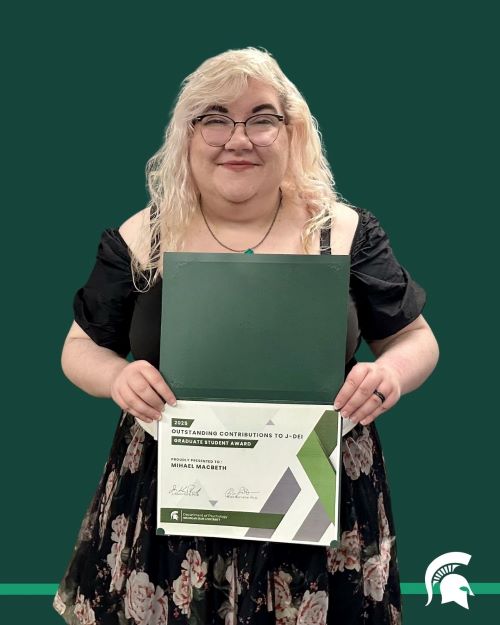 A green background with a cutout of Mihael MacBeth holding an award. The Spartan logo is in the bottom corner.