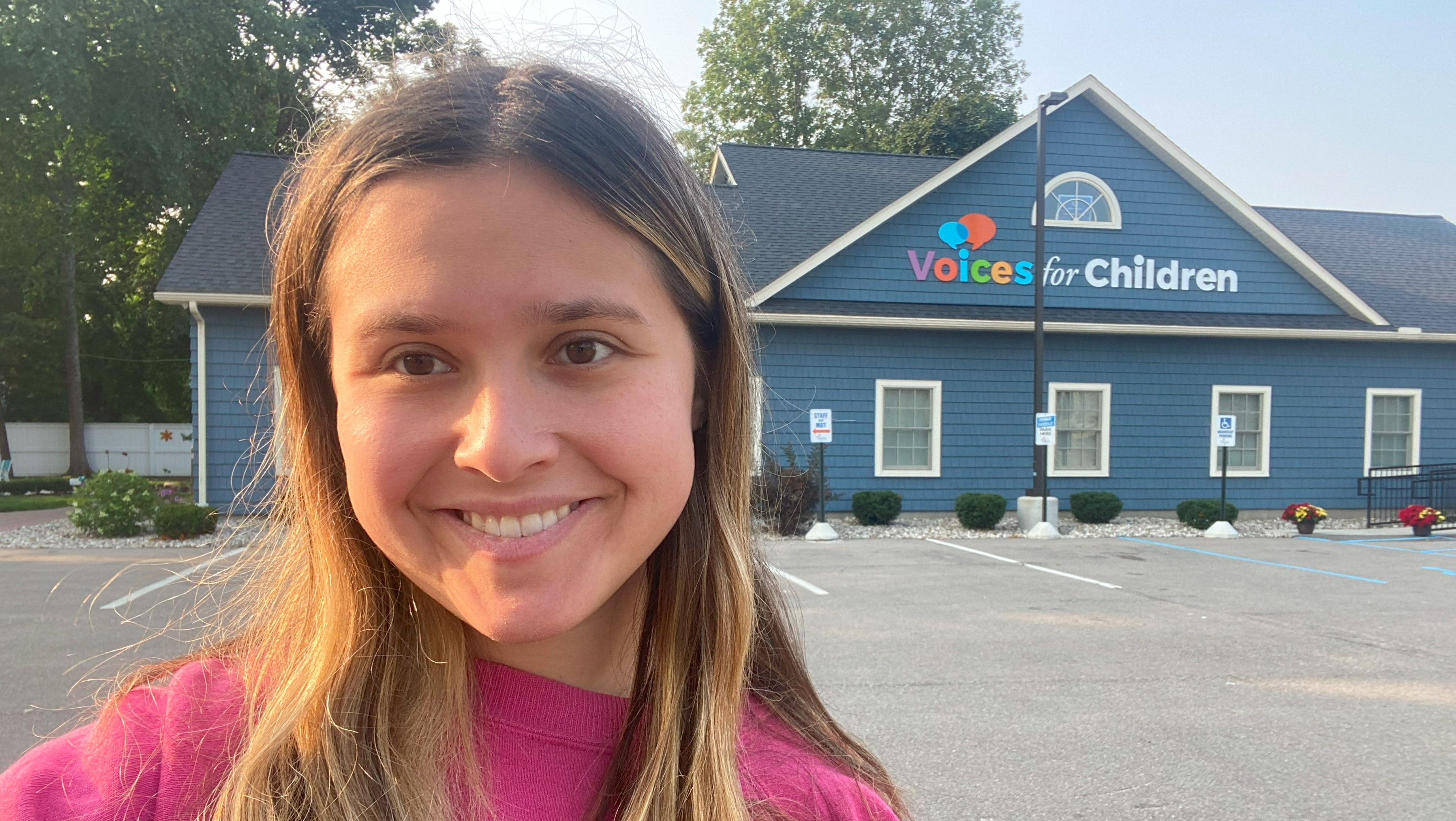 A smiling Olivia Feldman stands in front of the Voices for Children building