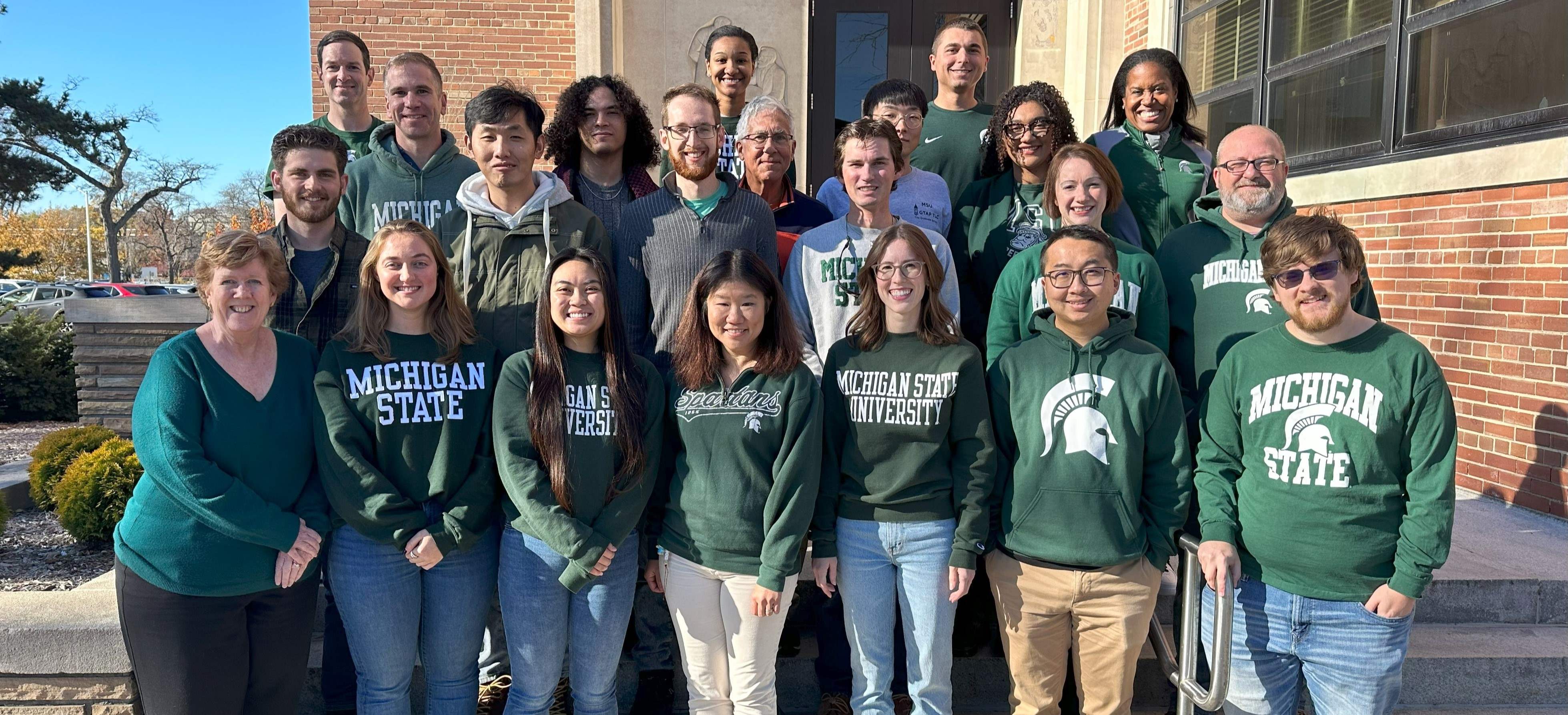 The 2023 Organizational Psychology faculty and graduate students stand together wearing Spartan gear.
