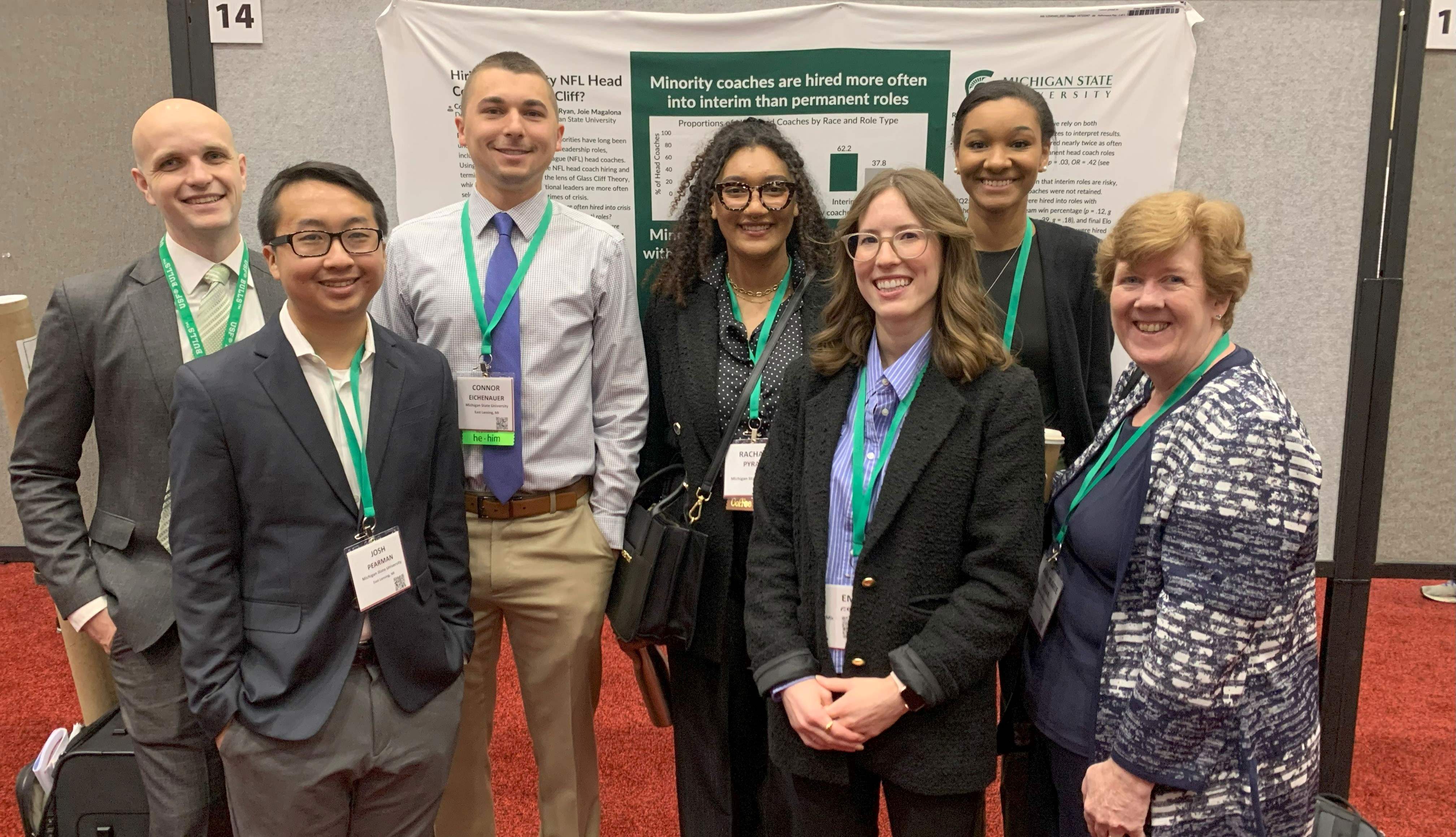 The Org Psych groups stands together in front of a grad student's poster presentation.