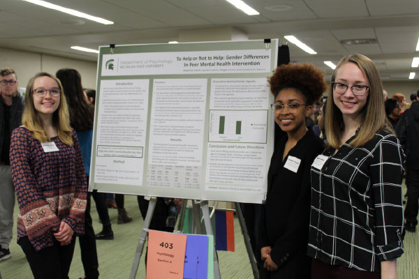 Psychology students smile with their research poster.