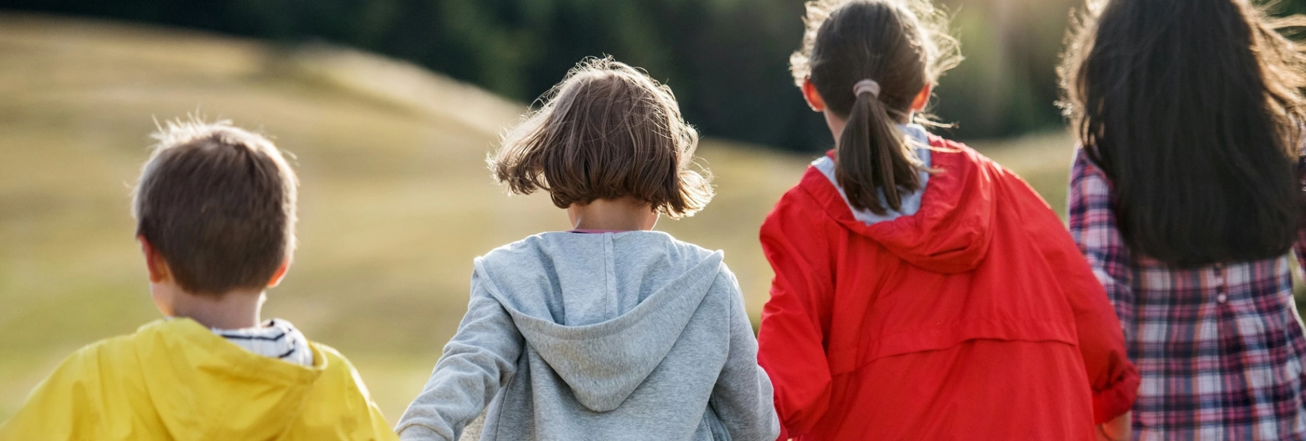 Four kids walk together with their backs facing the camera.