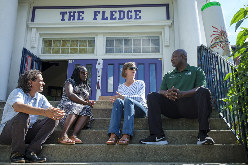 Carole Gibbs (Criminal Justice), speaks with fellow researchers Jennifer Cobbina (Criminal Justice), and Sean Hankins (Psychology) at The Fledge Community Center in Lansing. Jerry Norris, far left, runs The Fledge and is helping to facilitate their project titled "Putting Violence in Context: How Neighborhoods Shape Youth Decision Processes." Photo credit: Jacqueline Hawthorne, MSU.