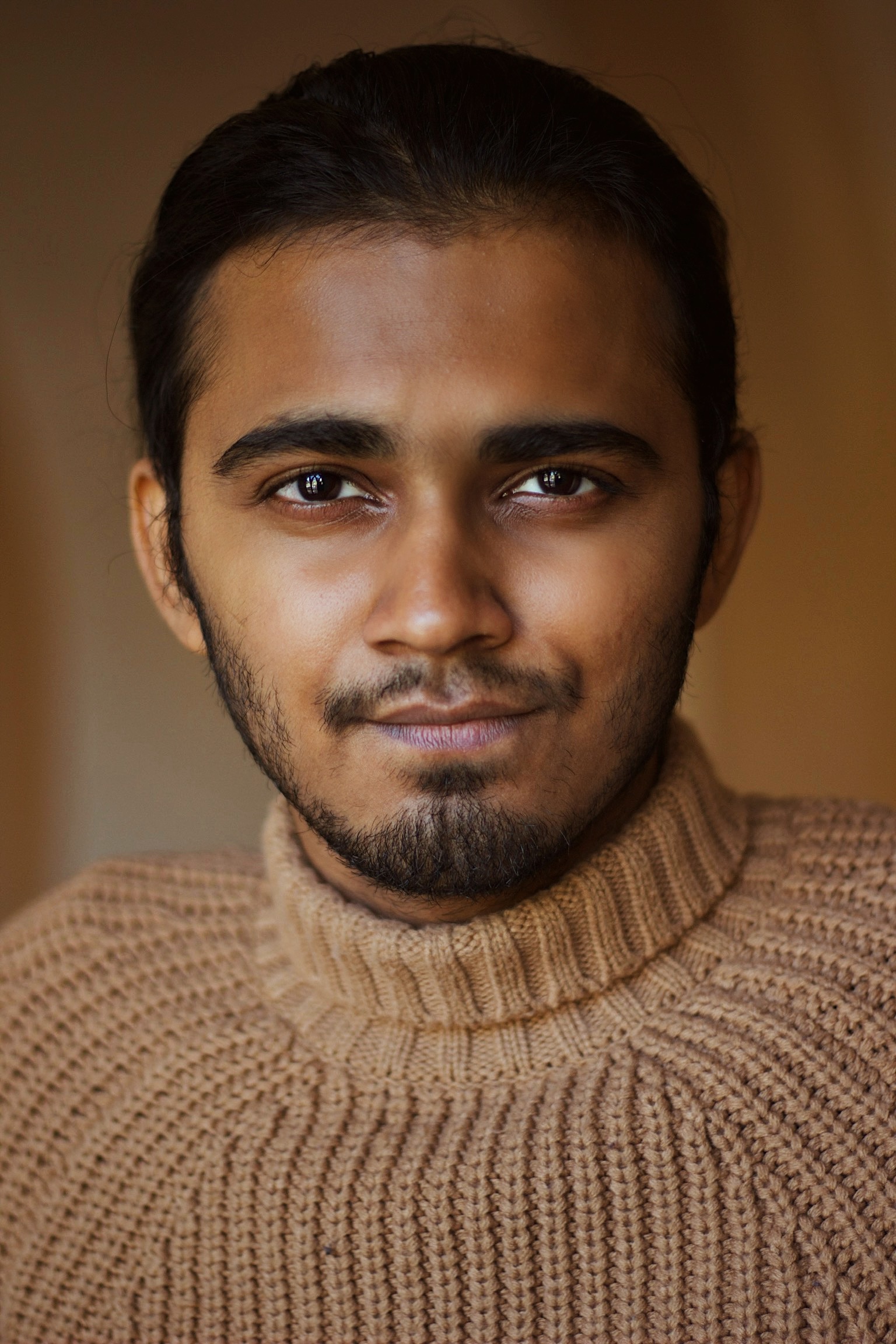 A headshot of Advait Rathi wearing a tan sweater and looking directly at the camera. 